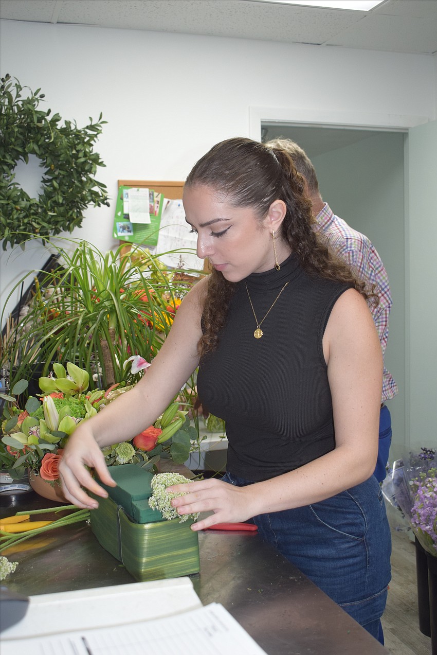 Employee Georgia Russell makes a floral arrangement at Le Gardenia Bleu.